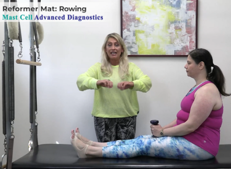 Instructor Sabrina Vaz demonstrates a motion for Dr. Pizano, who is holding small weights
